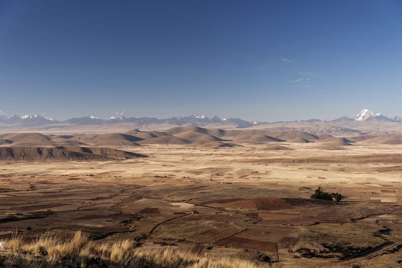 Panoramic view of the arid Andean plains with distant mountain ranges under a clear blue sky.