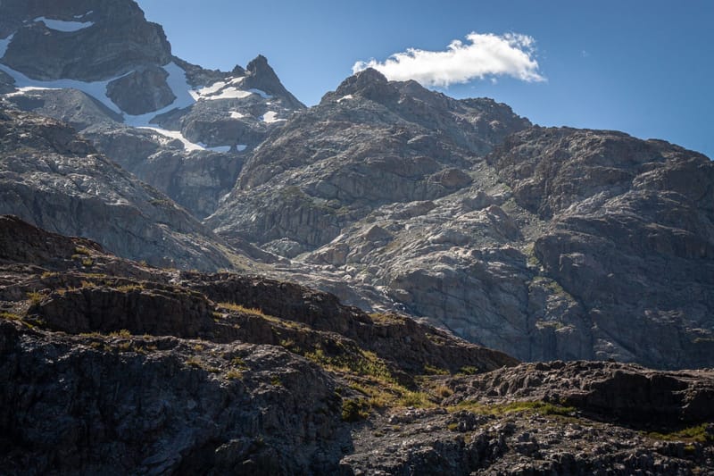 Breathtaking view of rugged mountains with snow patches under a bright blue sky.