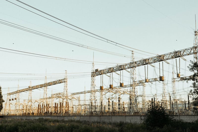 A wide view of an industrial electrical substation with power lines and towers outdoors.