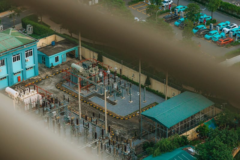An overhead view of a city electrical substation with surrounding infrastructure.