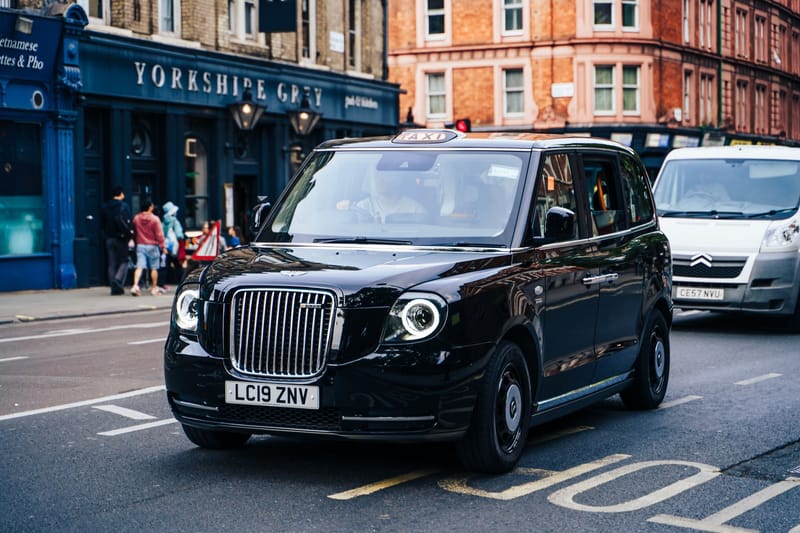 Iconic London black taxi driving through the city, highlighting British transportation.