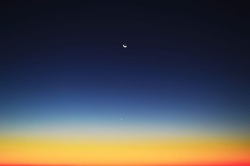 Crescent moon and planet visible in a colorful twilight sky over Mahajanga, Madagascar.
