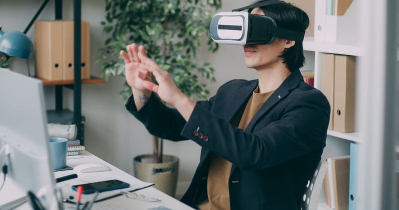A man in an office environment using a virtual reality headset, engaging with VR content.