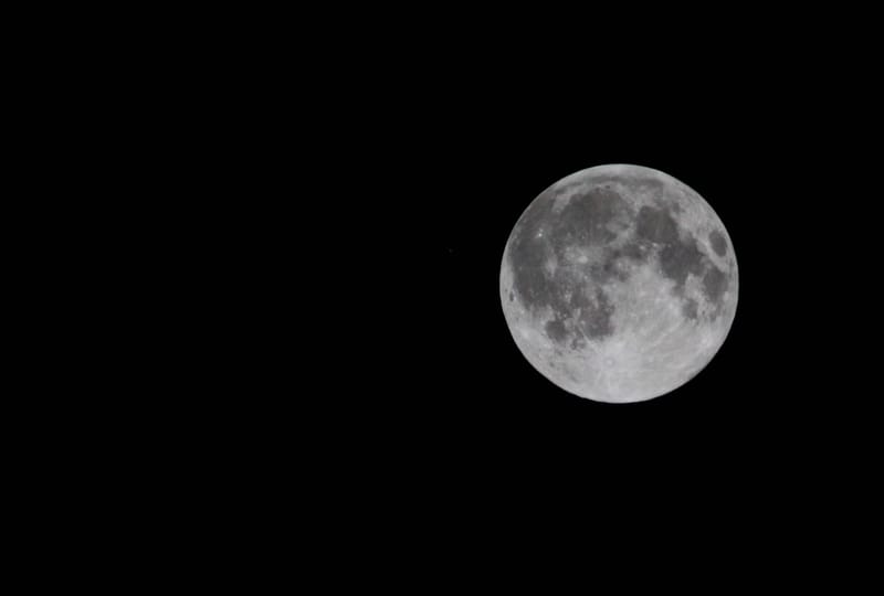 A full moon shines bright against a dark night sky, showcasing its details and craters.