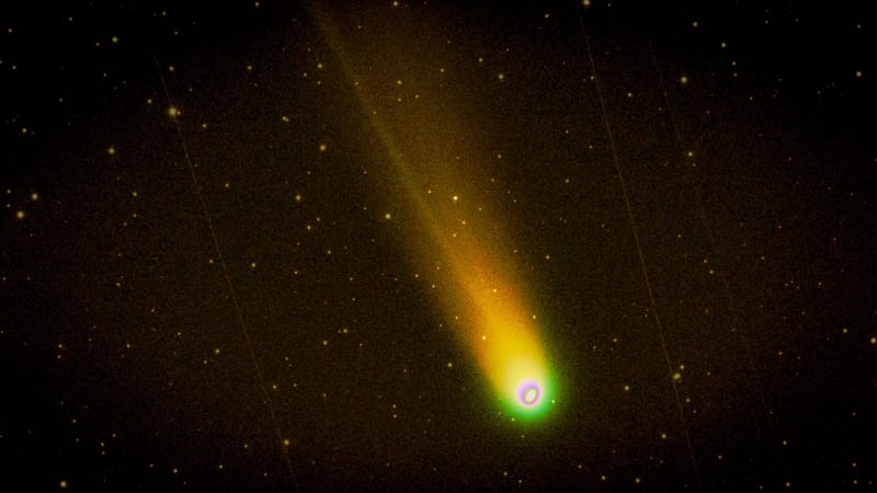Colorful comet with glowing trail streaking across a starry night sky.
