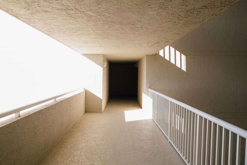 Empty hallway of modern light building with concrete walls and balcony with bright sunlight