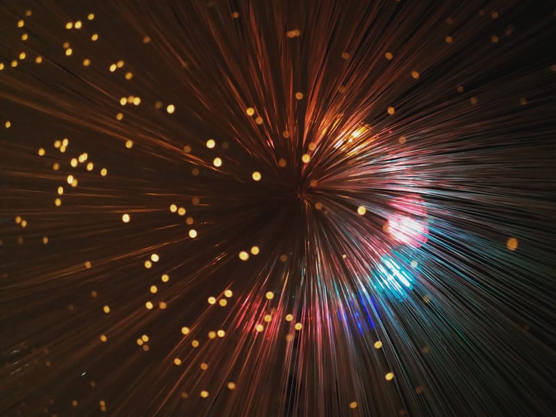 From below of abstract backdrop representing many thin colorful vertical lines shining near small spots on black background
