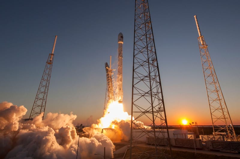Low angle of modern rocket taking off into cloudless sky during beautiful sunset over space factory