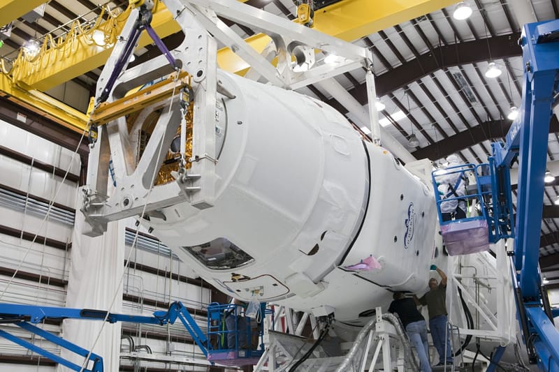 Low angle of unrecognizable technicians inspecting detail of new rocket booster at industrial space factory