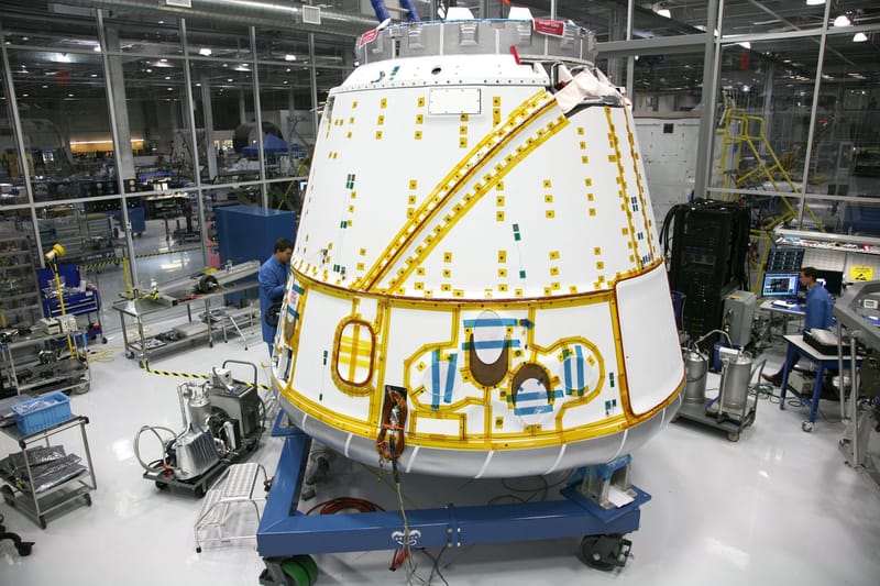 Anonymous male mechanic in uniform fixing detail of spacecraft while working at modern headquarter of industrial factory
