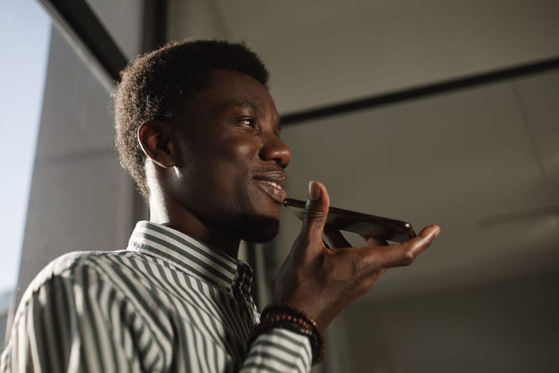 Smiling African American man talking on smartphone in an indoor setting.
