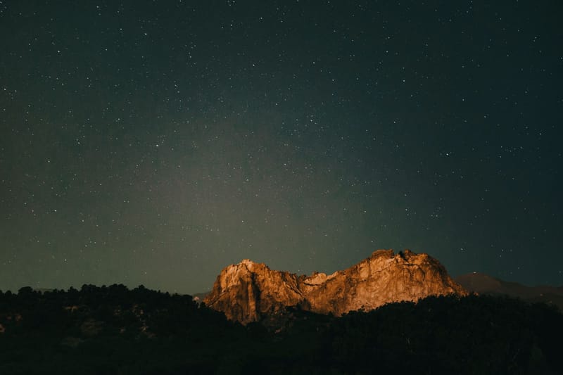 A serene night view of a mountain under a starry sky in Colorado Springs.