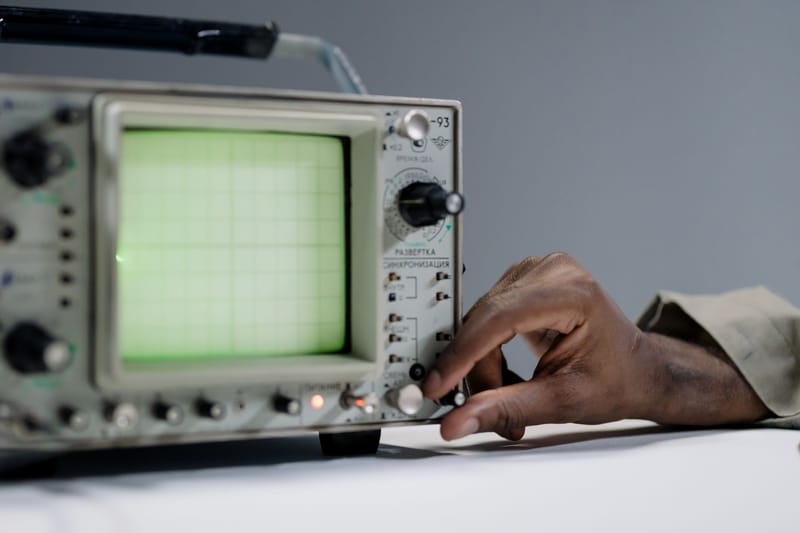 A person adjusts settings on a vintage oscilloscope in a studio environment.