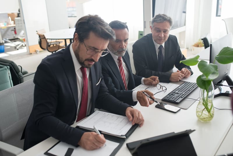 Three professionals collaborating on business plans in modern office.