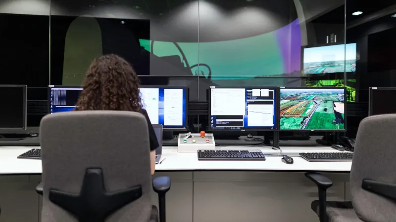 Female engineer managing multiple screens during a technology simulation in a control room.