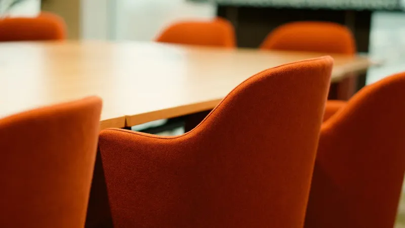 Close-up view of modern orange chairs around a conference table in an office setting.