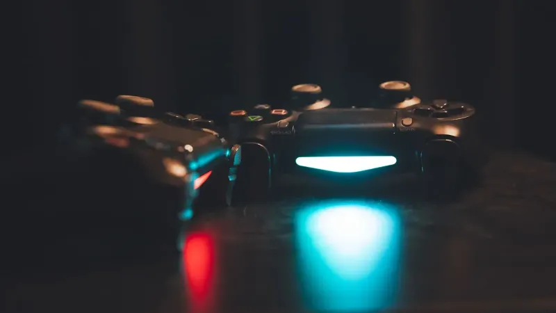 Close-up of glowing gaming controllers on a dark surface, creating a moody ambiance.