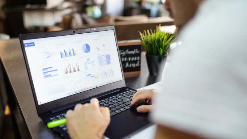 Focused business analysis with charts and graphs on a laptop in a modern office setting.
