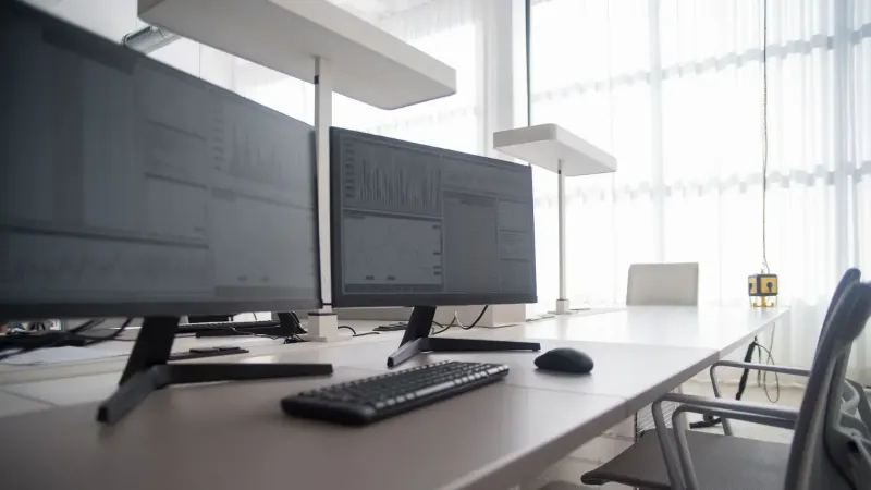 Stylish contemporary office featuring multiple computer monitors and ergonomic chairs.