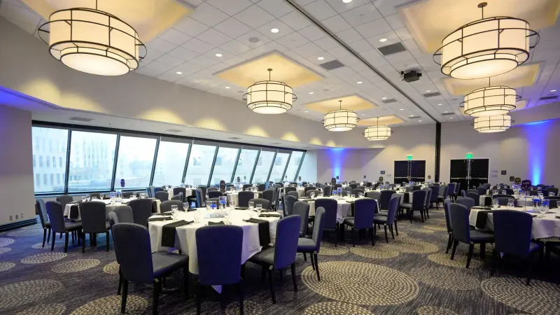 Spacious banquet hall featuring elegant dining tables set for a formal event under modern lighting.