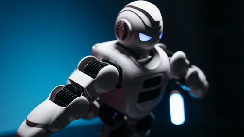 Dynamic shot of a futuristic robot with glowing eyes in a dark studio, showcasing innovation.
