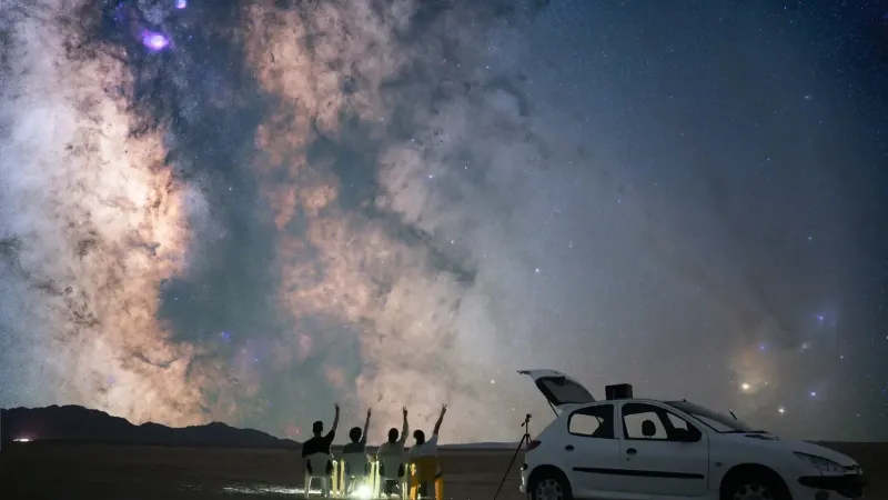 A group of stargazers observing the Milky Way in Semnan, Iran with a car and telescope.