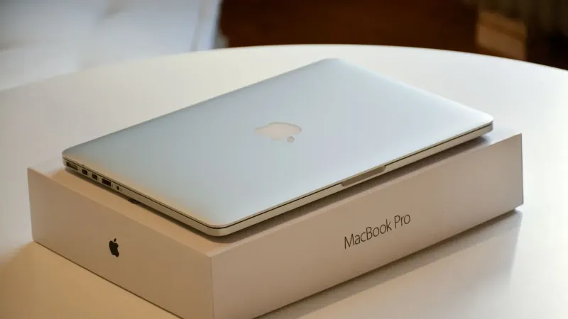 Una computadora portátil MacBook Pro colocada en su empaque original sobre una mesa interior blanca.