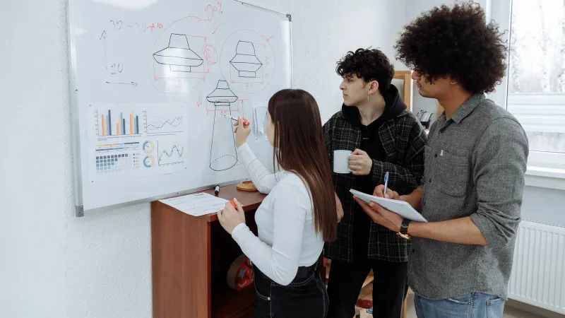 Young professionals brainstorming and designing a product prototype on a whiteboard.