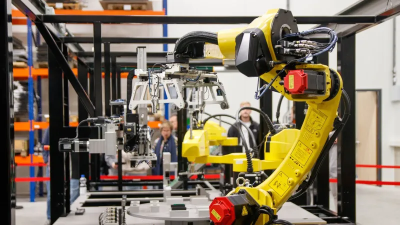 Close-up of a yellow industrial robotic arm in action at a modern manufacturing facility.