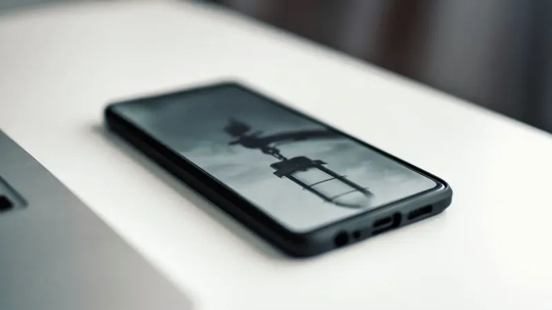 Close-up de un smartphone que muestra una imagen borrosa, colocada en un escritorio junto a una computadora portátil.
