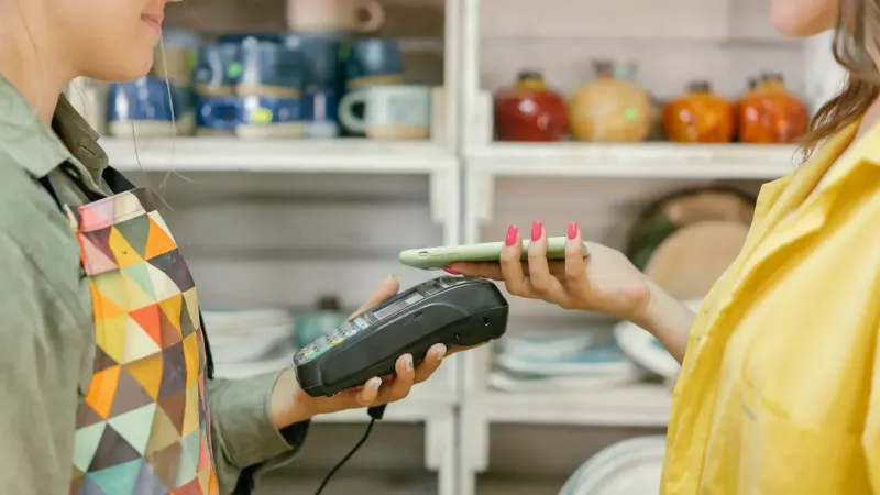 Un cliente realiza un pago sin efectivo usando un teléfono inteligente en una tienda minorista. La tecnología moderna cumple con la comodidad.