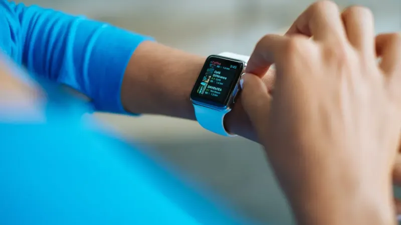 Person interacting with a smartwatch, showing a fitness application on the screen.