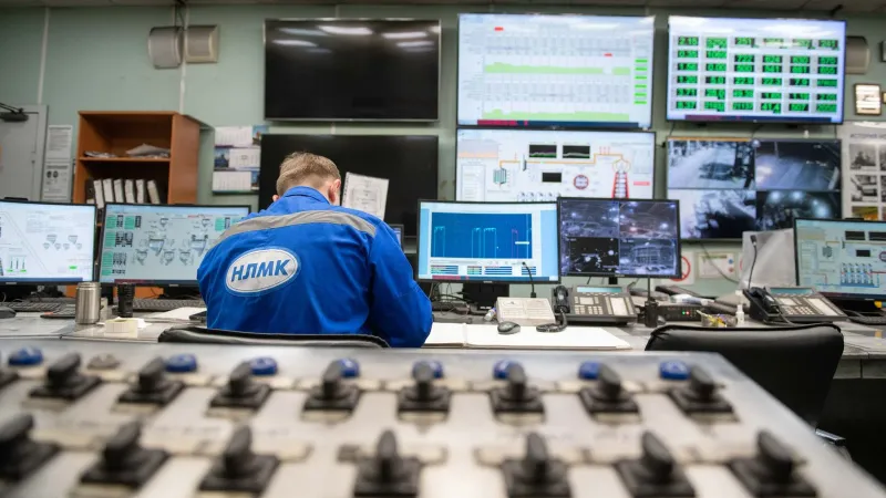 An engineer monitors multiple screens in an industrial control room, ensuring smooth operations.