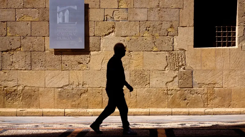 Silhouette of a man walking by Museo de la Catedral wall in Murcia, Spain.