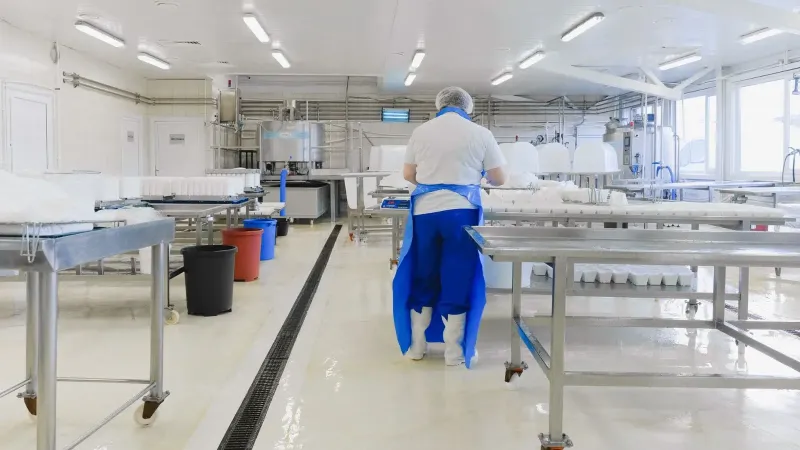 A person wearing protective clothing working in a bright, sterile laboratory environment.