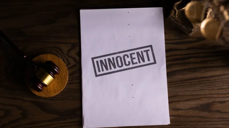 Close-up of legal document stamped 'Innocent' beside a gavel on a wooden desk.