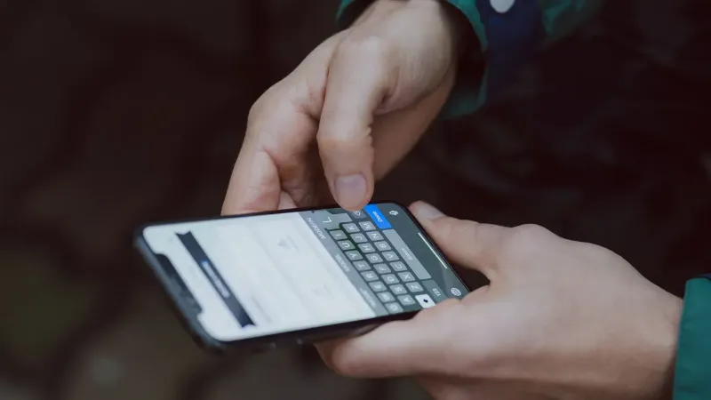 Close-up of person texting on a smartphone. Outdoor setting with wireless connectivity.