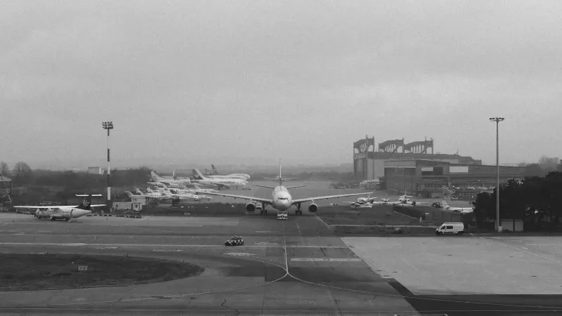 Vista monocromática del aeropuerto de Belgrado con varios aviones, capturando la actividad de aviación urbana.