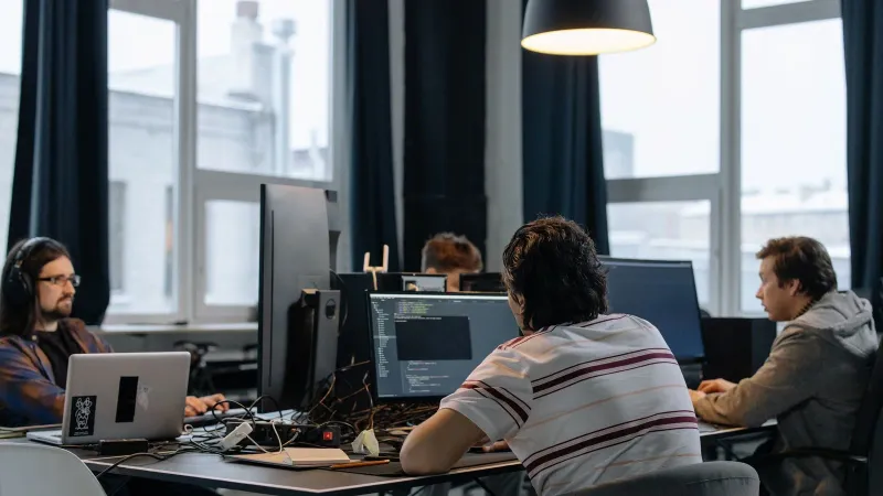Team of developers working together on computers in a modern tech office.