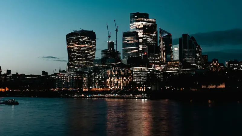 Breathtaking view of London's illuminated skyline at dusk, reflecting on the Thames River.