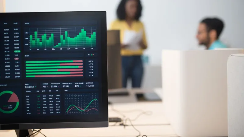 Modern office with financial trading screens and a diverse team discussing strategies.