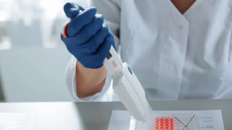 Close-up of a scientist using a pipette in a lab with a focus on sterile procedures.