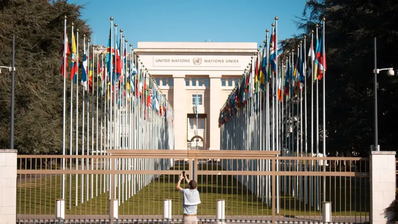 El hombre fotografía la oficina de las Naciones Unidas con banderas internacionales en Ginebra, Suiza.