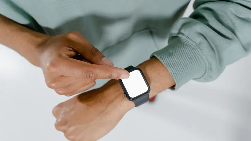 Close-up of a person in a green sweater using a smartwatch.