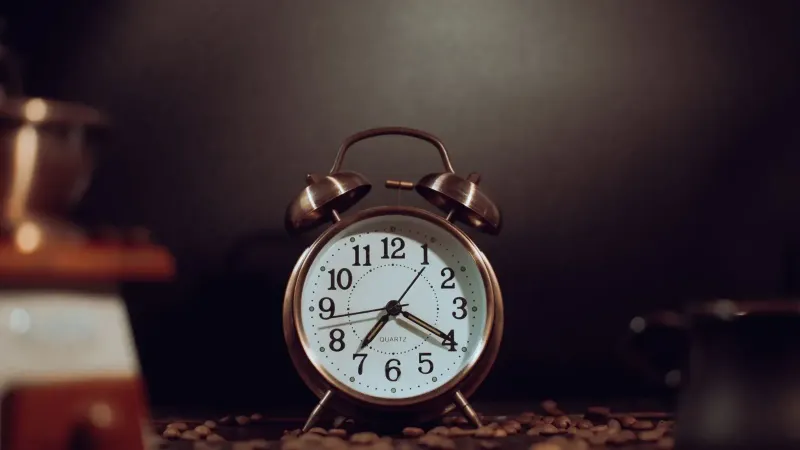Rustic vintage alarm clock surrounded by coffee beans, providing a warm nostalgic feel.