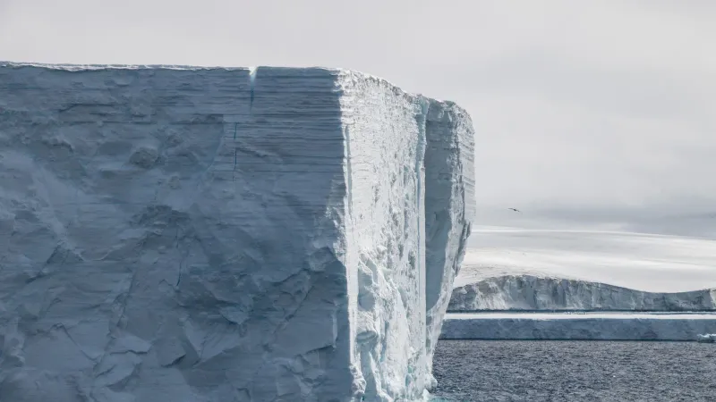 A breathtaking view of a massive iceberg in Antarctica surrounded by the deep blue sea.