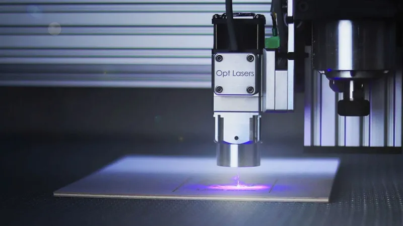 Close-up of a laser engraver working on a surface under blue lighting.