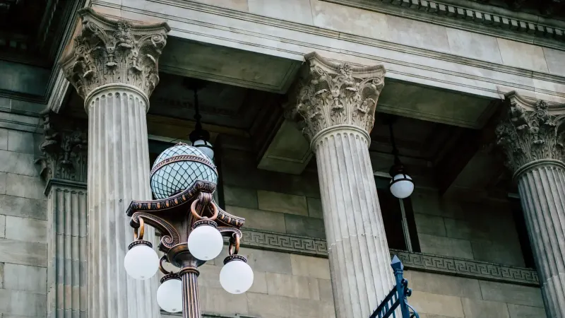An elegant view of classic architectural columns with an antique street lamp, ideal for urban landscapes.