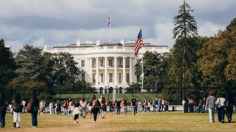 Los turistas se reúnen fuera de la Casa Blanca en un día soleado, capturando la grandeza del hito.