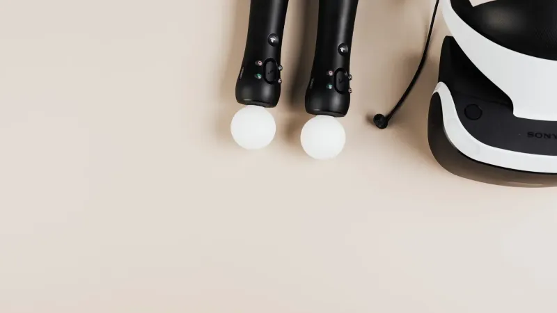 Top view of gaming controllers and VR headset on neutral background.